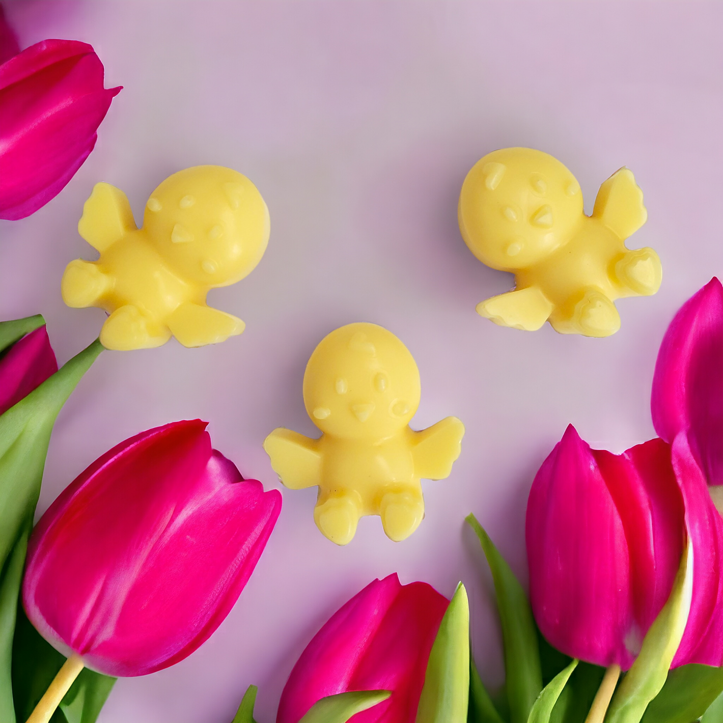 Three yellow baby chicks soy wax melts with pink tulips in the background.